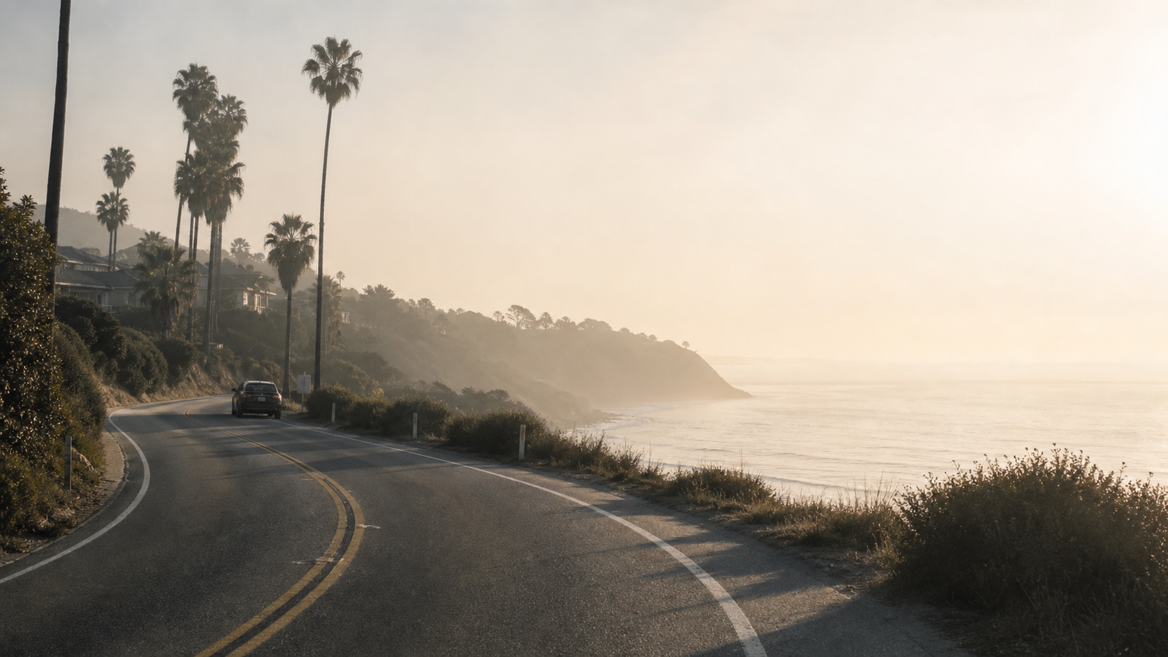 slow coastal road through white haze and pale sky